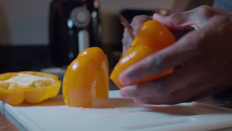 Cook-slicing-and-cleaning-fresh-yellow-bell-pepper-on-plastic-white-cutting-board