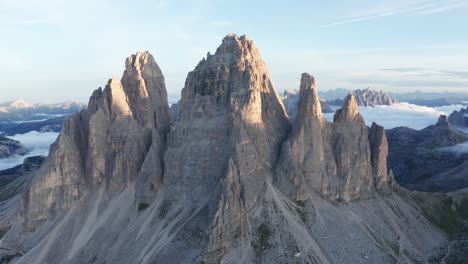 Aerial-approaching-shot-of-famous-Tre-Cime-Di-Lavaredo-Summits-in-Italy-during-sunrise---Beautiful-cloud-ceiling-in-background---high-angle-flight