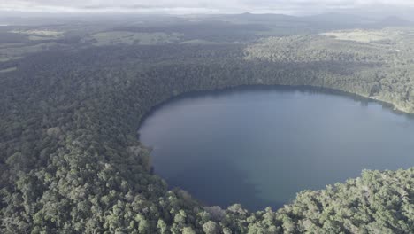 Aerial-View-Of-Lake-Eacham-On-A-Foggy-Day-In-Atherton-Tableland,-Queensland,-Australia---drone-shot