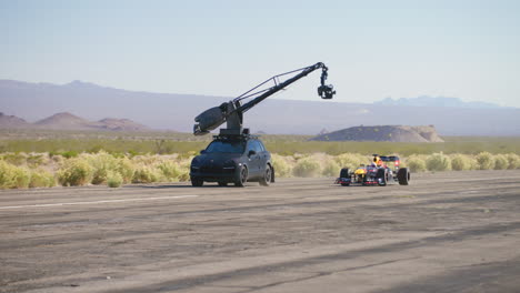 Arm-car-cinema-camera-follows-and-films-Formula-1-car-driving-down-an-airport-runway-in-Las-Vegas,-Nevada