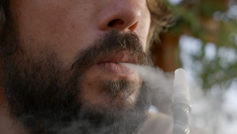 closeup-of-bearded-young-man-inhaling-and-exhaling-an-electronic-cigarette