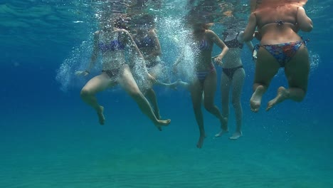 Unterwasser-Zeitlupenszene-Einer-Gruppe-Von-Freundinnen,-Die-In-Kristallklarem-Meerwasser-Schwimmen