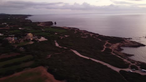 Aerial-view-of-Calasetta-coastline,-pan-right-reveals-offshore-lighthouse