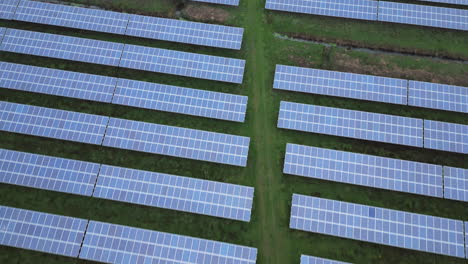 Solarpark-Auf-Einer-Grünen-Wiese,-Endlose-Muster,-Diagonale-Linien,-Langsamer-Rückwärts-Drohnenflug
