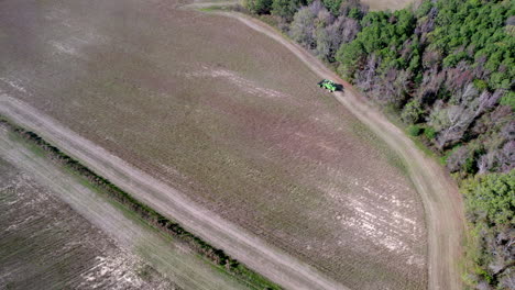 Drone-footage-of-soy-bean-harvesting-on-a-farm-field-with-a-harvester-or-tractor,-wide-rotating-aerial-shot