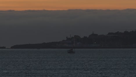 Sunset-over-city-and-marine-in-Cascais-with-white-boat-sailing,-Portugal