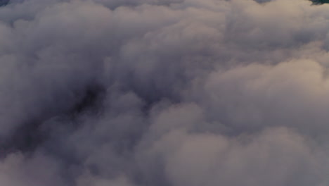 Haunting-clouds-surrounding-Tre-Cime-mountain-peak-aerial-view-tilt-up-across-South-Tyrol-Dolomites-landscape