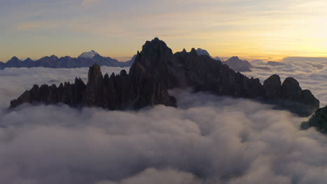 Stunning-ethereal-clouds-surrounding-Tre-Cime-ghostly-Dolomites-mountain-range,-Sunrise-orbiting-aerial-view