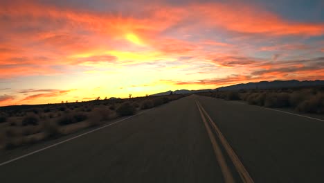 Atemberaubender-Goldener-Sonnenuntergang-Während-Der-Fahrt-Durch-Die-Mojave-Wüste-Mit-Joshua-Bäumen-In-Der-Silhouette