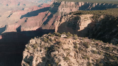 Aerial-flight-over-Grand-Canyon-lookout-point,-tilt-up-revealing-distant-plateau