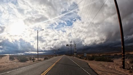 Driving-along-a-remote-Mojave-Desert-road-on-a-stormy,-overcast-day---driver-point-of-view