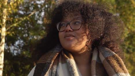 Smiling-Black-woman-with-curly-hair-portrait-video-in-autumn-forest