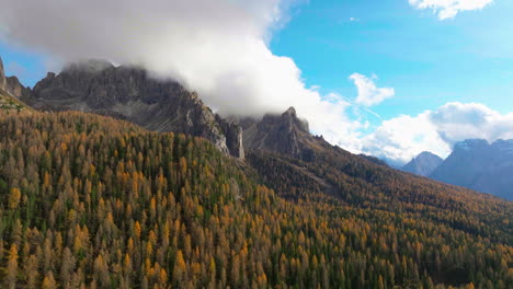 Elevándose-Por-Encima-De-Los-árboles-Del-Bosque-De-Tre-Cime-Y-El-Pico-De-La-Montaña-Del-Tirol-Del-Sur-Cubierto-De-Nubes-Iluminadas-Por-El-Sol-En-La-Distancia