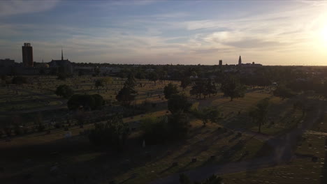 Arcing-aerial-shot-of-the-sun-setting-over-a-graveyard