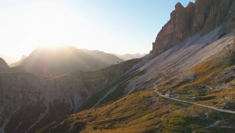 Sunrise-over-South-Tyrol-peaks-aerial-view-following-winding-road-on-mountain-slope