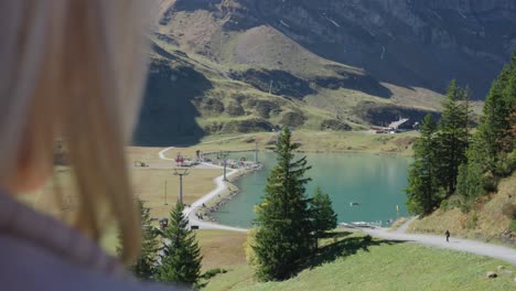 Woman-enjoys-view-of-clear-lake-in-a-beautiful-mountain-setting-on-a-sunny-day-in-Engelberg,-Switzerland
