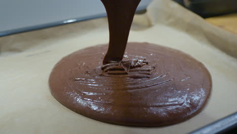 Close-up-Pouring-Chocolate-Dough-Into-Baking-Dish-with-a-Baking-Paper-on-the-Bottom-in-Slow-motion