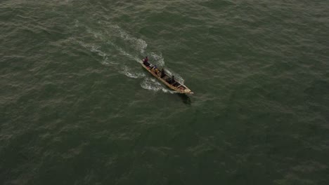 Aerial-shot-focused-on-a-fishing-boat,-with-one-of-the-fishermen-bailing-water-with-a-bucket