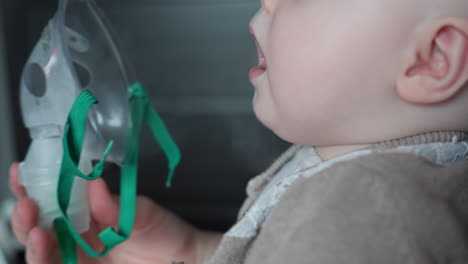 Mother-holds-inhaler-mask-on-8-month-baby-and-Toddler-girl-breathes-the-vapor-medicine-at-home