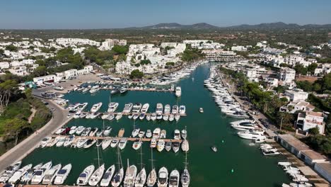 Aerial-view-with-drone-flying-back-over-the-harbor-of-Cala-d'Or-located-on-Mallorca-with-boats-and-yachts