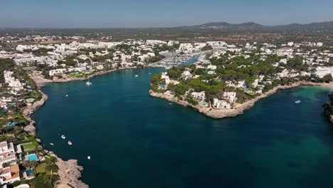 Aerial-view-of-drone-flying-to-cala-d'Or-harbor-and-beach-of-Mallorca-filled-with-boats-and-yachts