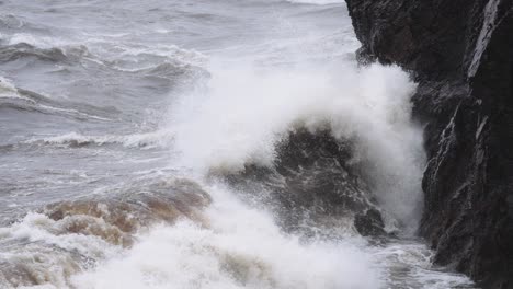 Raue-Wellen-Während-Eines-Sturms,-Der-In-Zeitlupe-Auf-Felsige-Küstenklippen-Stürzt