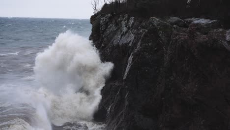 Stormy-waves-crash-against-granite-coastal-rocky-cliffs-in-slow-motion