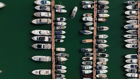Top-down-aerial-view-taken-with-drone-of-a-boat-leaving-the-dock-of-Cala-d'Or,-Mallorca