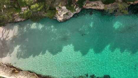 Top-down-aerial-view-taken-with-drone-of-a-small-relaxing-beach-with-crystal-clear-waters