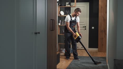 Ein-Männlicher-Professioneller-Reiniger-Reinigt-Einen-Teppich-Mit-Einem-Kabellosen-Staubsauger