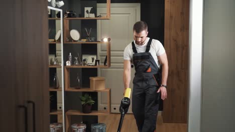 Close-up-of-a-man-in-a-uniform-cleaning-with-a-cordless-vacuum-cleaner