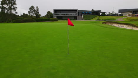 Rote-Golfmastfahne-Auf-Gepflegtem-Grün-Am-Golfplatz-Mit-Bunker
