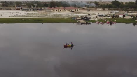 Toma-Aérea-De-Un-Pequeño-Bote-Con-Turistas-Haciendo-Un-Recorrido-En-El-Lago-Dakar,-Senegal