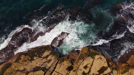 Top-view-of-multiple-blue-green-ocean-waves-smashing-against-rocky-coastline-in-Australia