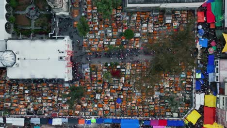 Aerial-view-over-a-church-and-a-decorated-graveyard,-during-all-saints-day-in-Mexico-city---overhead,-drone-shot