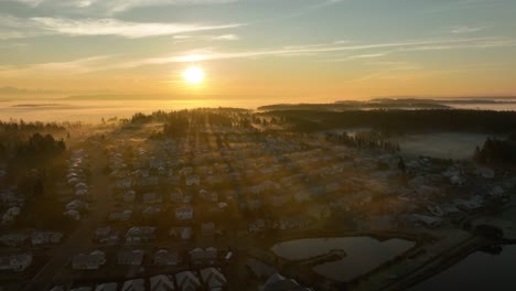 Wide-aerial-view-of-the-sun-rising-over-a-dense-suburban-neighborhood-on-Whidbey-Island