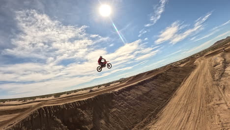 Off-road-motorcyclist-takes-on-a-big-jump-at-a-dirt-racetrack-in-the-Mojave-Desert---aerial-slow-motion