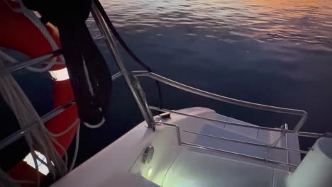 Von-Einem-Bootsdeck-Mit-Beleuchtetem-Rettungsring-In-Stilles,-Dunkles-Wasser-Blicken