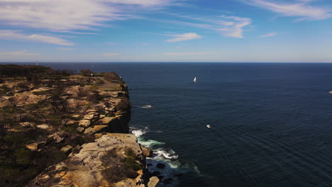 Sheer-rocks-dropping-off-to-boats-in-the-sea-drone-shot