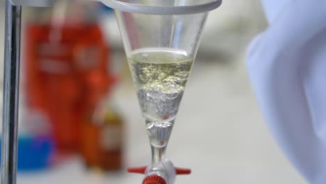 Science-chemistry-lab-test,-close-up-as-a-lab-tech-pours-liquid-into-a-funnel