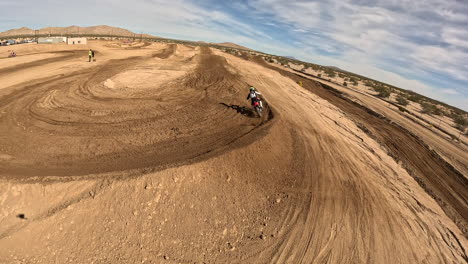 Motorcyclists-racing-around-a-dirt-racecourse-and-making-huge-jumps---first-person-view-from-a-drone