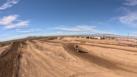 A-motorcycle-makes-long-jumps-while-racing-along-a-dirt-racecourse---first-person-view-drone-follow