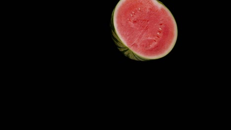 Die-Hälfte-Der-Wassermelone-Fällt-In-Zeitlupe-Einzeln-Auf-Schwarzem-Hintergrund
