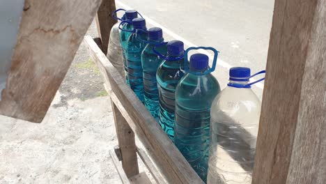 Plastic-bottles-of-petrol-fuel-gasoline-for-sale-at-local-kiosk-fuel-station-shop-on-the-Timor-Leste-and-Indonesia-border,-Southeast-Asia