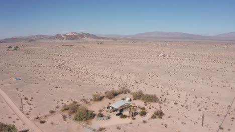 Aerial-shot-panning-above-a-lone-house-in-the-middle-of-a-barren-desert-in-California