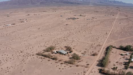 Descending-close-up-panning-aerial-shot-of-a-lone-house-in-the-empty-Mojave-Desert-in-California