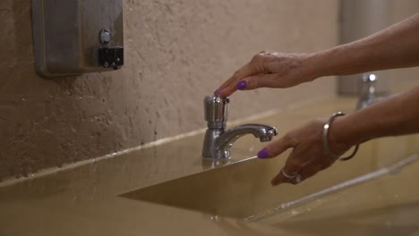 Woman-washing-hands-in-outdoor-public-restroom