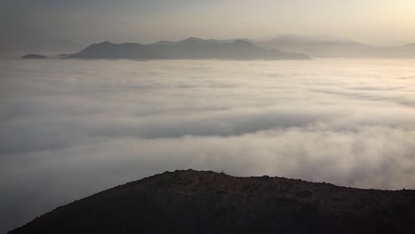Ascending-drone-shot-of-a-group-of-hikers-above-the-clouds-in-a-hill-of-Lima-Peru