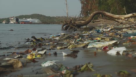 Water-pollution-along-the-Ganga-River,-discarded-litter-and-trash-that-has-washed-up-onto-the-riverbank-destroying-the-natural-beauty-of-the-area,-Panjim,-India