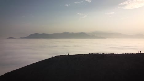 Silhouette-drone-shot-of-hikers-in-the-mountains-above-the-clouds-during-sunrise-in-Lima-Peru
